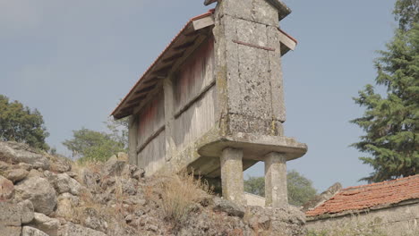 low angle revealing a granary called espigueiro in a rural village on a hill friaes tras-os-montes portugal