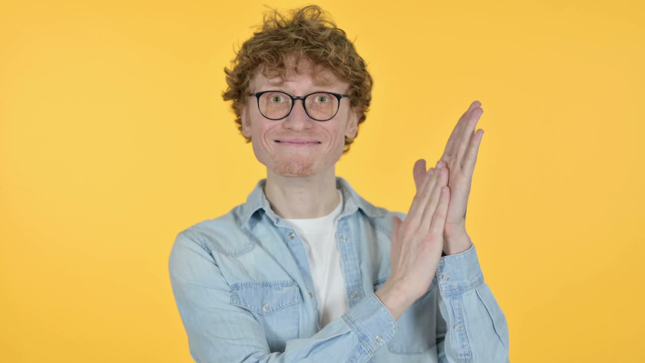aplaudiendo joven pelirrojo aplaudiendo, aplaudiendo sobre un fondo amarillo