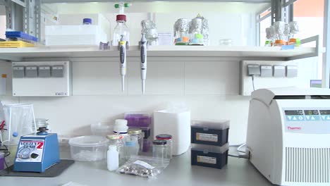 Dolly movement through a molecular biology laboratory we see a lab coat a scientist works with a laptop placed at his lab table