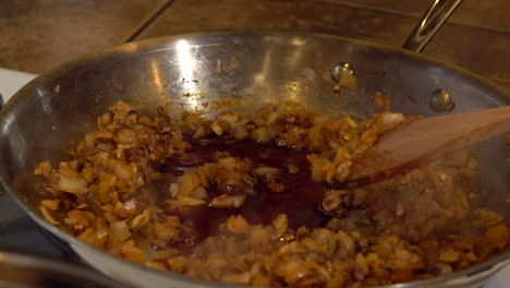 adding soy sauce to diced onions and carrots and stirring in frying pan, closeup