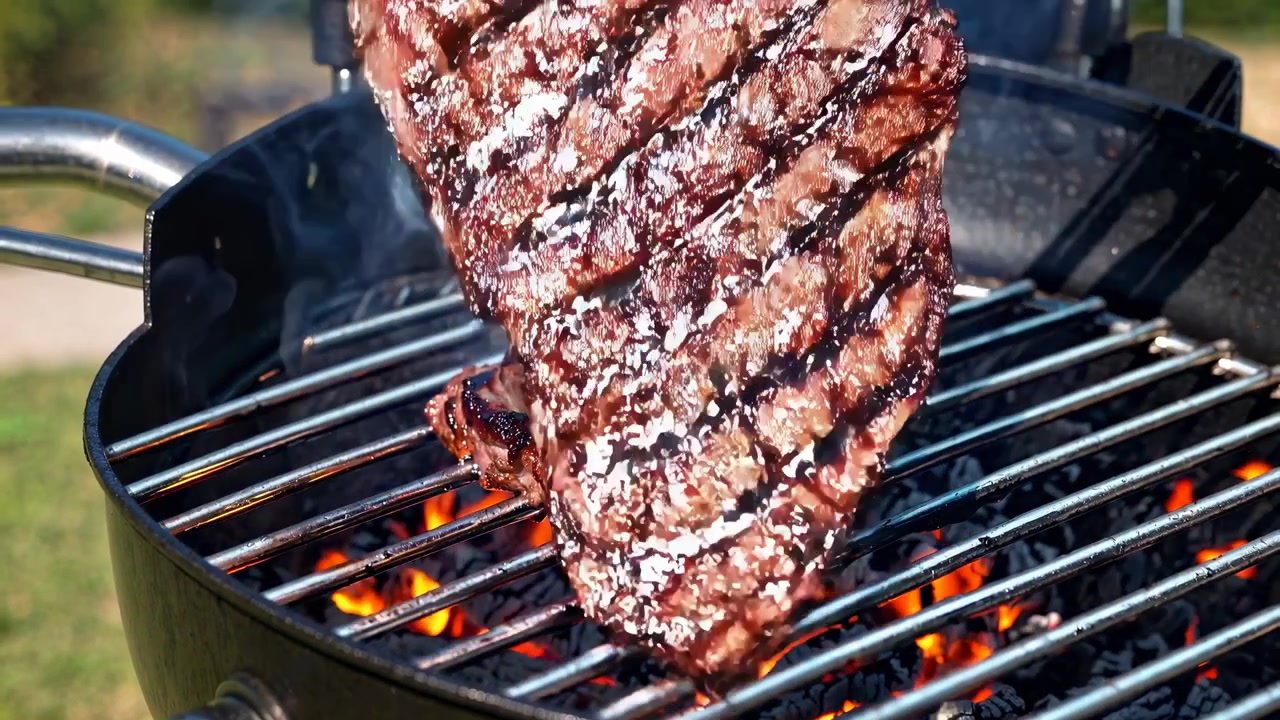 Girare una deliziosa bistecca su una griglia a carbone ardente