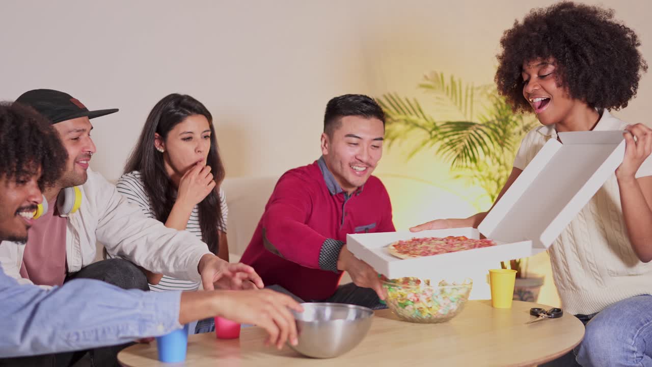Diverse group of friends sharing pizza and snacks at a casual home gathering