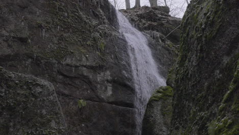 slow motion stationary shot of a waterfall running down a rocky cliff in northeastern ohio shot from below