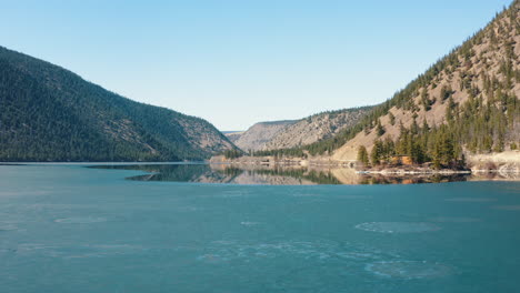 Aerial-fly-over-semi-frozen-lake-in-a-mountain-valley-in-Fall