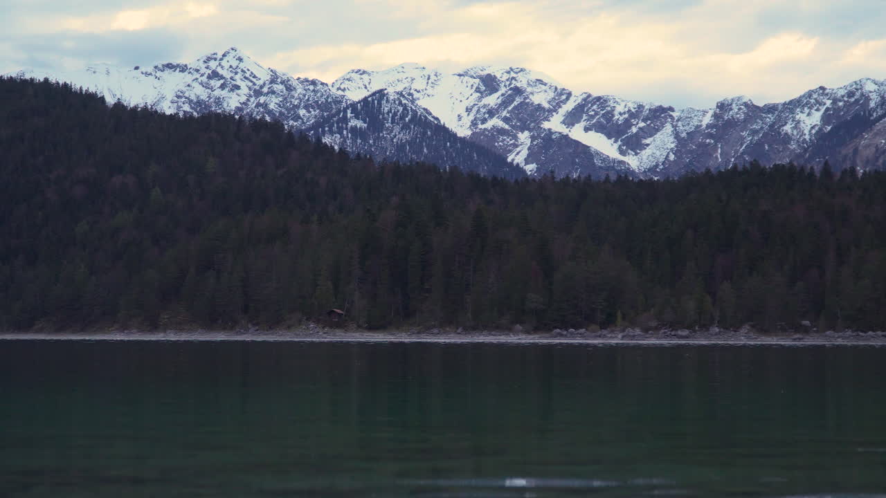 el pacífico lago eibsee agua ondulante y la costa del bosque arbolado bajo la majestuosa cordillera nevada del glaciar