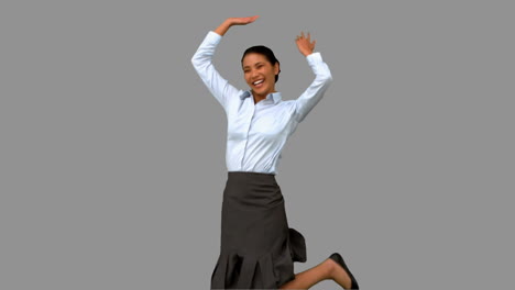 Happy-businesswoman-raising-arms-on-grey-screen