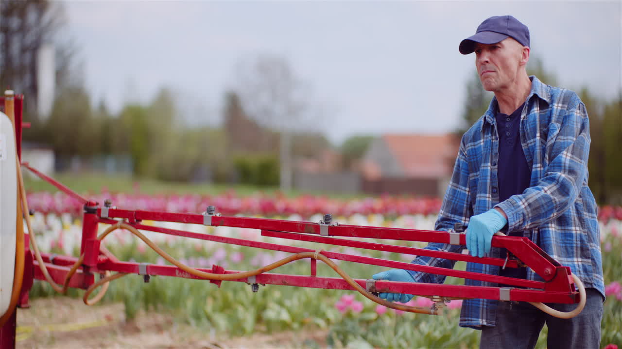 Agriculteur ajustant la rampe de pulvérisation dans un champ de tulipes.