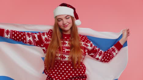 Adult girl patriot in christmas sweater waving and wrapping in israel national flag celebrating