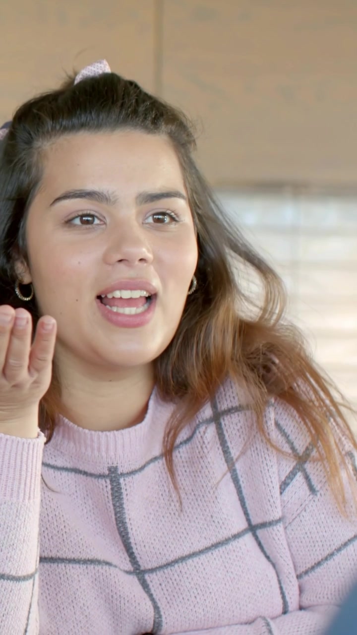 Video verticale: Inizia un discorso, una donna spiega, gesticolando al tavolo della cucina, mostrando uno smartwatch