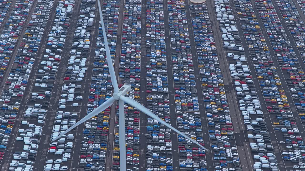 Centro de comercio de vehículos con turbina eólica girando sobre hileras de coches