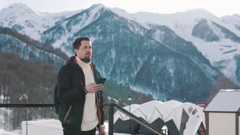 man using phone in snowy mountains