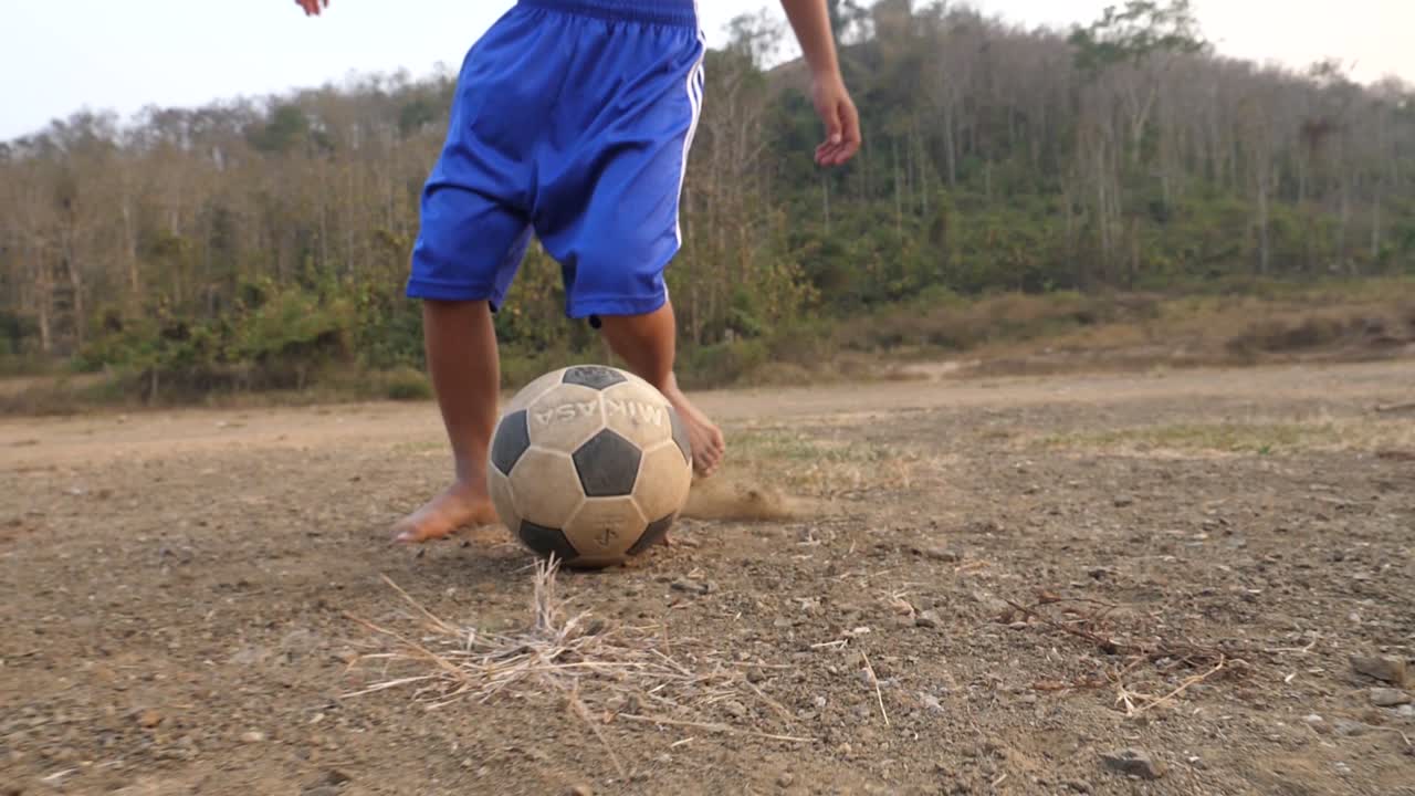 Child playing soccer in a rural field