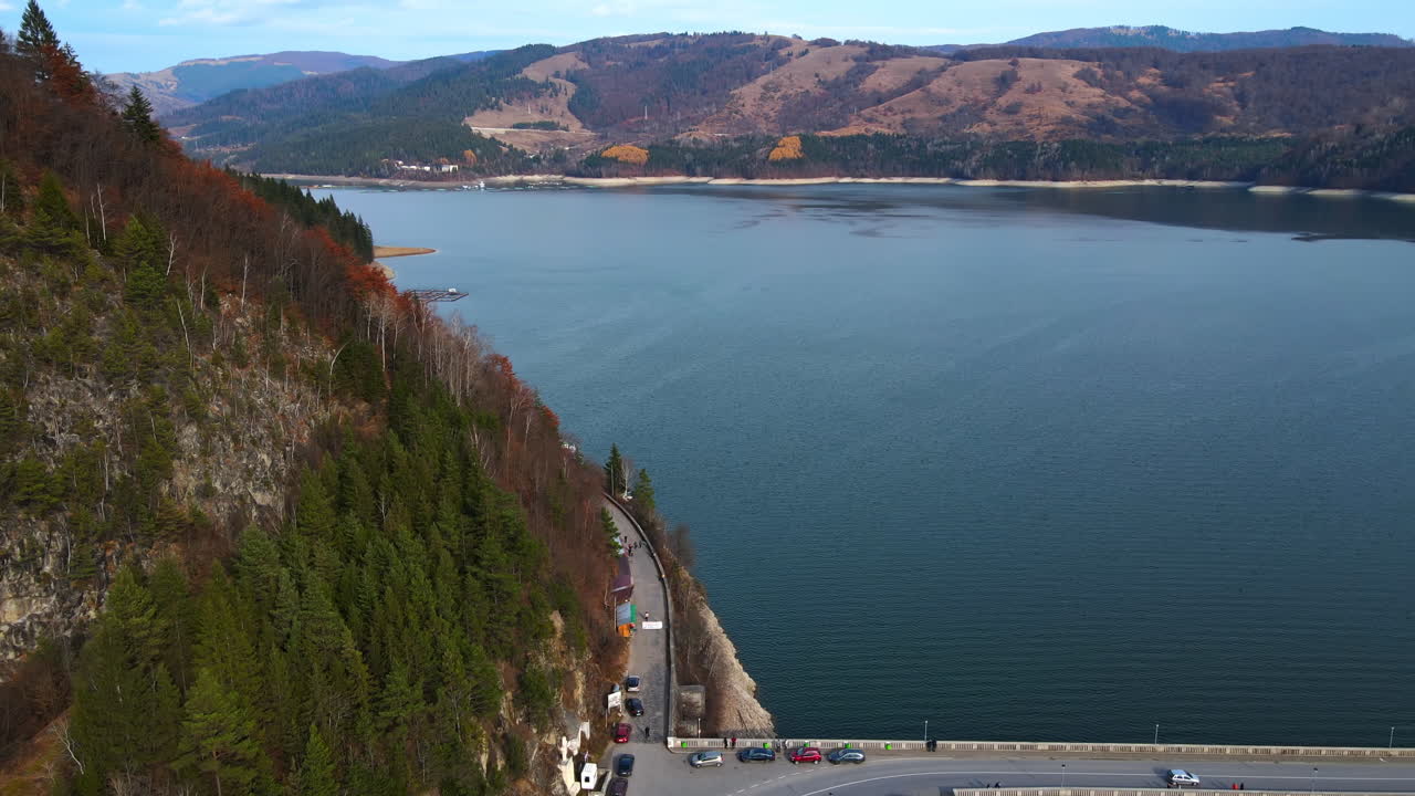 Aerial drone view of Bicaz lake and dam with cars in Romania. Hills covered with lush forest