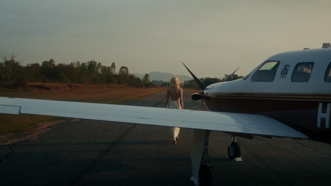 Woman Walking Towards a Small Plane at Sunset