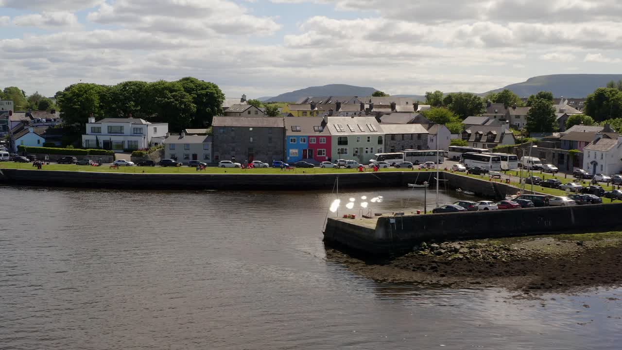 Aerial orbit of Kinvara Pier, colorful houses, and quays
