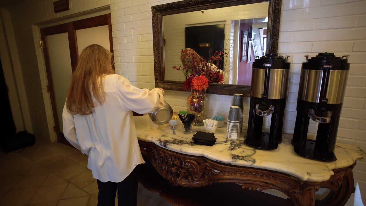 Woman pouring water into a cup next to coffee makers