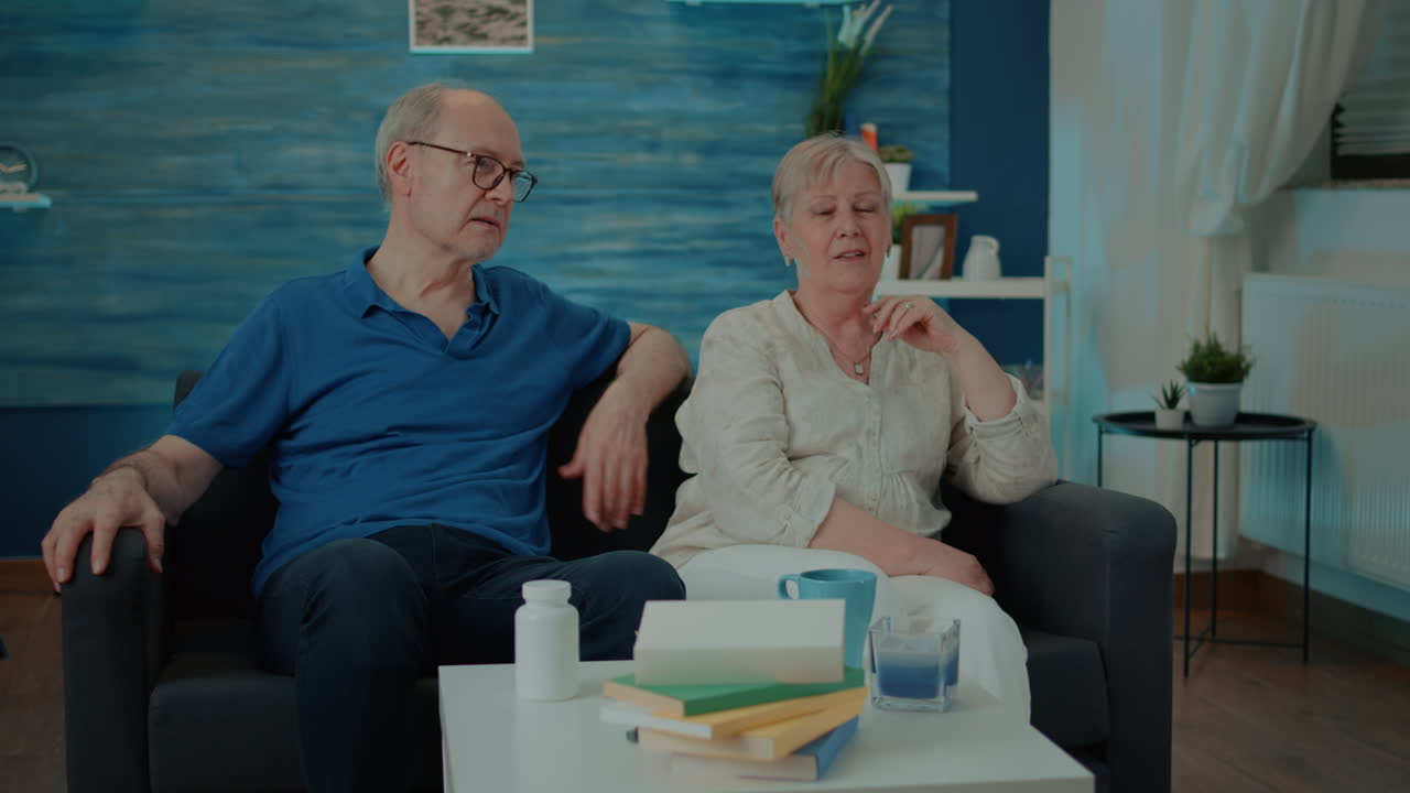 Elderly couple watching TV in their living room