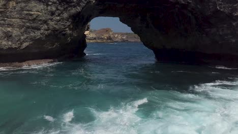 aerial view of the crystal blue water of broken bay in nusa penida, indonesia with the waves hitting the cliffs