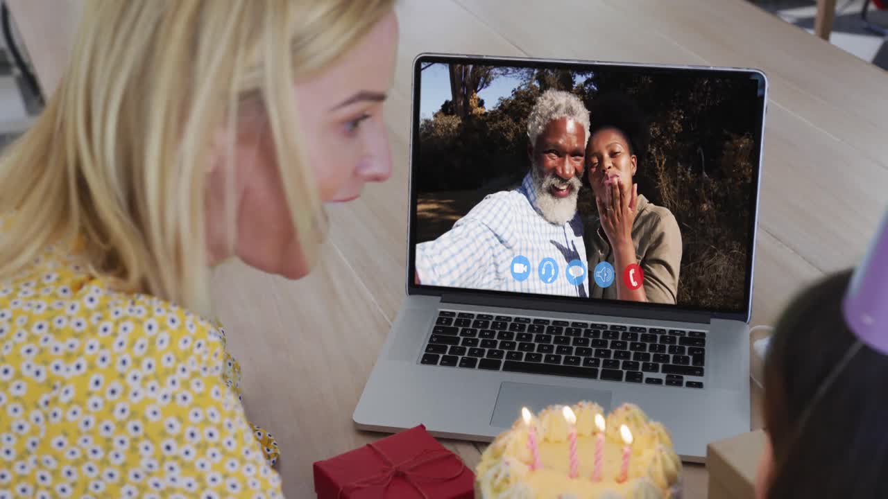 madre y hija caucásicas celebrando su cumpleaños mientras hacen una videollamada en una computadora portátil en casa