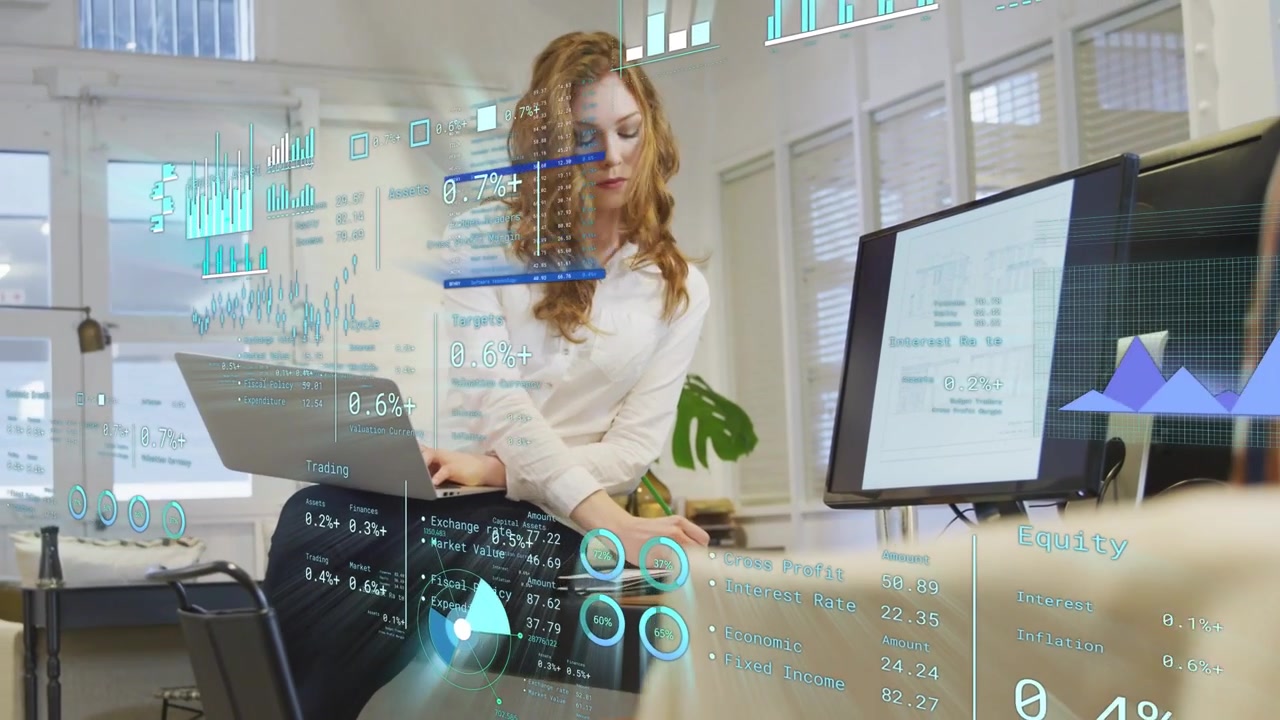 Woman sitting on desk edge typing on laptop, activating AR finance charts and analyzing metrics