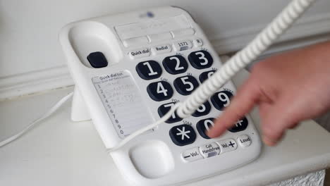 man dialling a number on a landline phone