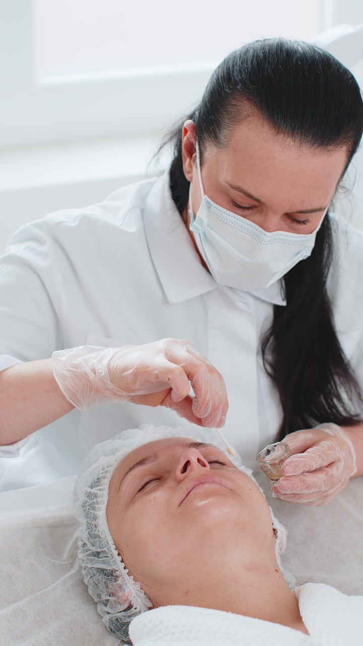 미용사는 여성의 눈 주변 피부에 보습성 질 산을 적용합니다. 노화 방지 치료