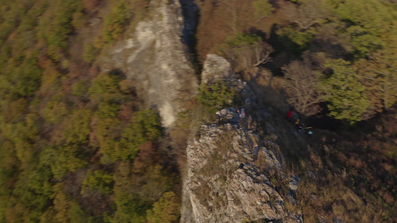 People hiking and reaching the top of the cliff with epic view of river estuary beneath them, on the sunset. Fast Aerial pivot shot.
