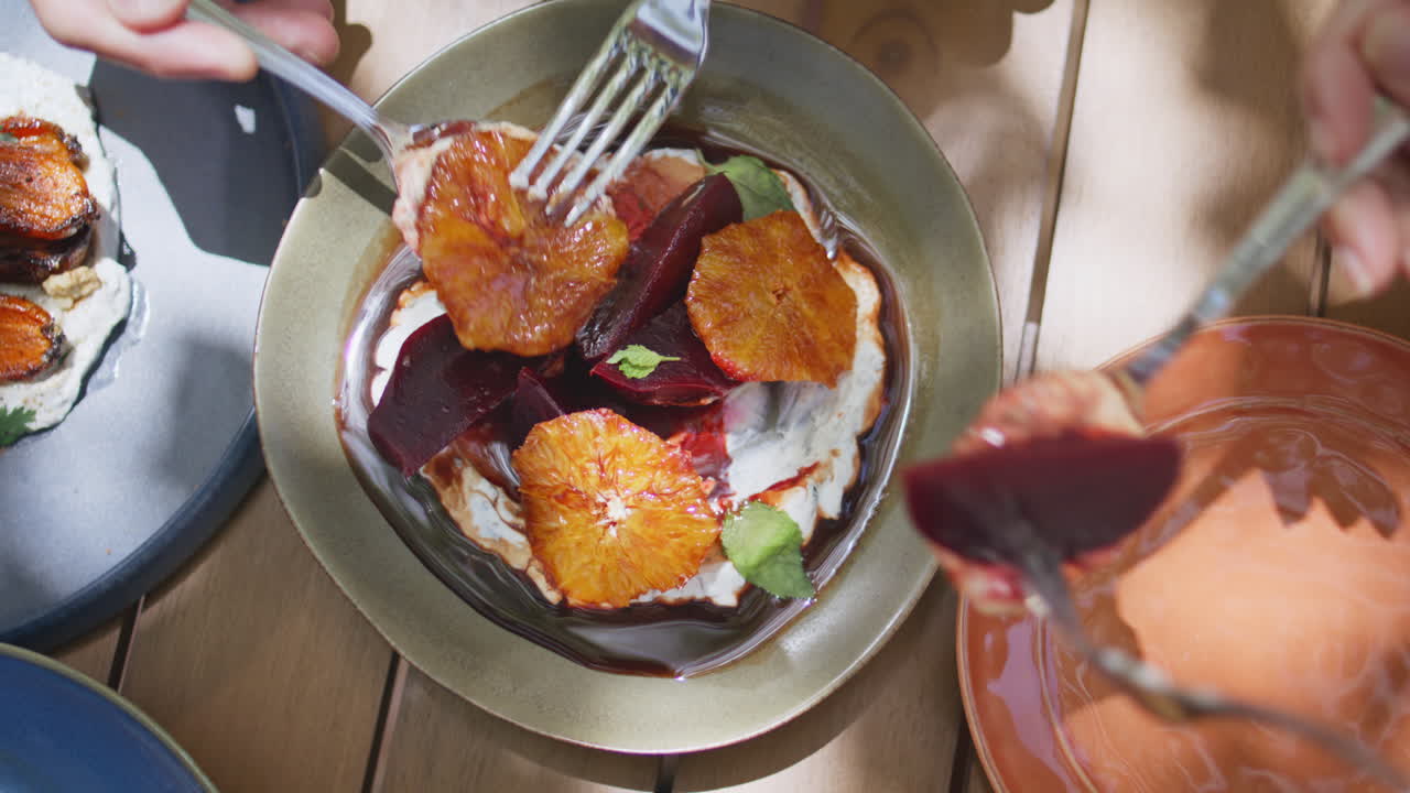 manos de primer plano tomando una comida con cucharas y tenedor en un restaurante vegano