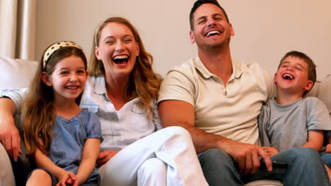 Happy-young-family-laughing-on-couch