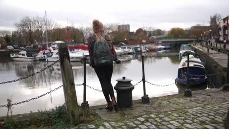 woman smiling into the camera and then starts looking at the waterside of bristol harbour