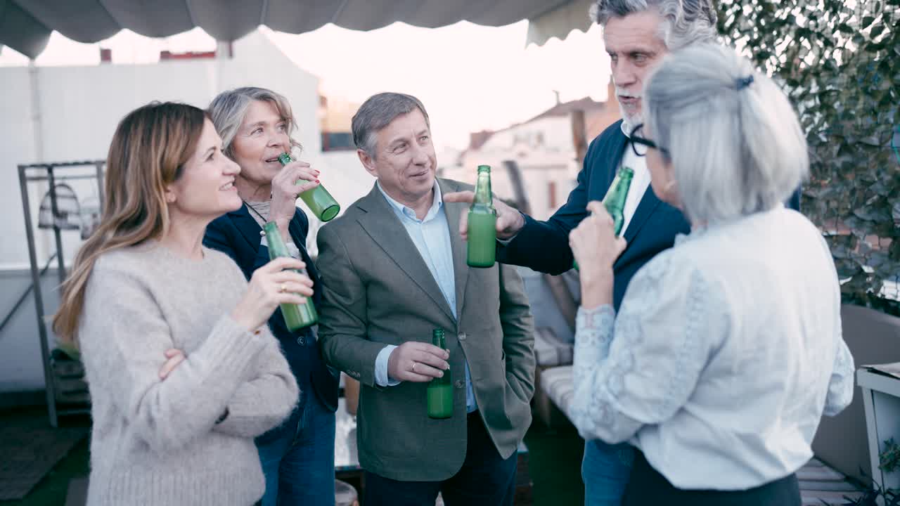 屋上テラスで交流し、お酒を飲む幸せそうな友人グループ