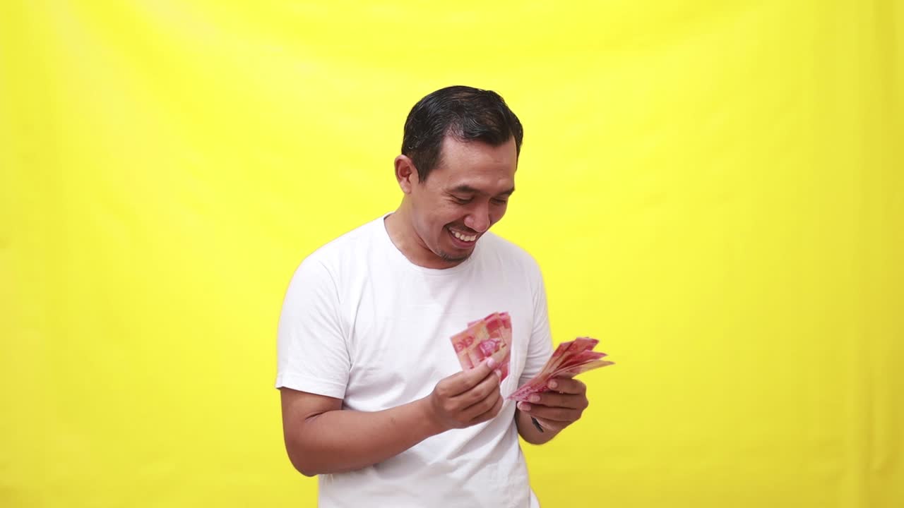 Glücklicher asiatischer erwachsener Mann zählt indonesische Banknoten