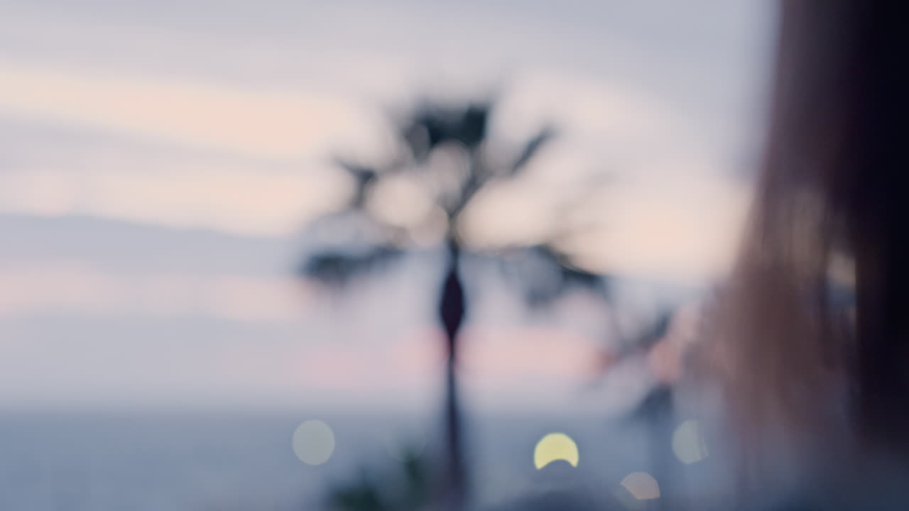 행복한 여성이 커튼을 열고 아침 일출을 즐기고 집에서 평화로운 자유를 느끼고 휴가에서 휴식을 취하고 아름다운 바다 전망을 바라보고 있습니다.