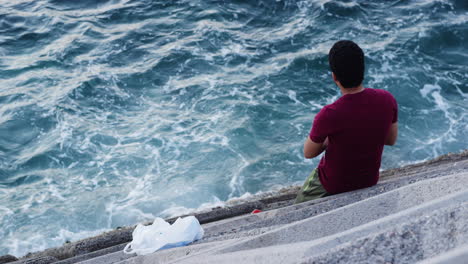man in front of a choppy ocean coast, muscat, oman, medium high angle shot