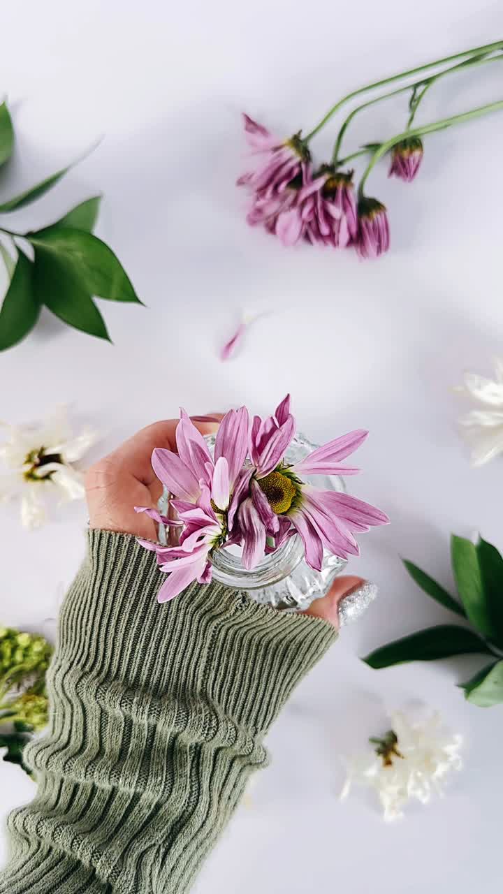 Mano di donna che tiene un vaso di fiori viola