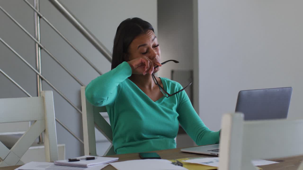 Tired african american woman using laptop while working from home