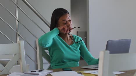 tired african american woman using laptop while working from home