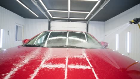 man worker washing red car on a car wash.