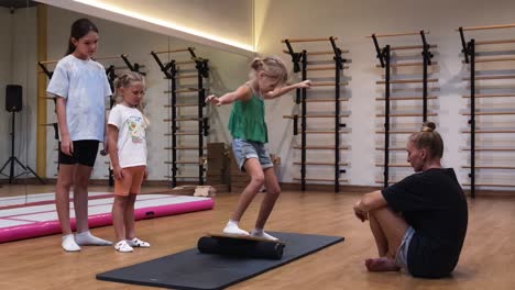niños equilibrando en una tabla de equilibrio con un instructor