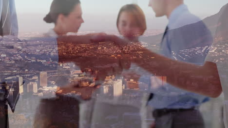 mid section of businessman and businesswoman shaking hands at office over aerial view of cityscape