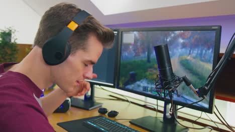 man gaming at home sitting at desk putting on headphones for live stream