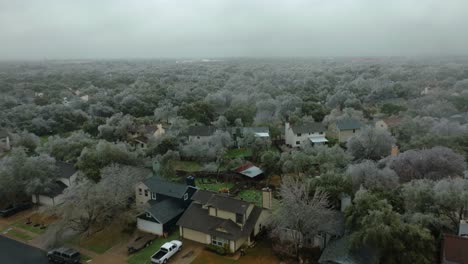 frozen icy trees in austin texas suburban neighborhood during cold winter freeze, aerial drone flyover south austin homes in 4k
