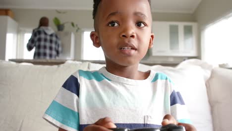 Feliz-Niño-Afroamericano-Sentado-En-El-Sofá-Y-Jugando-Videojuegos,-Cámara-Lenta