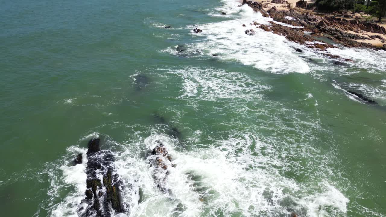 Slow motion cinematic drone tilt up flying over ocean with tropical resort in distance