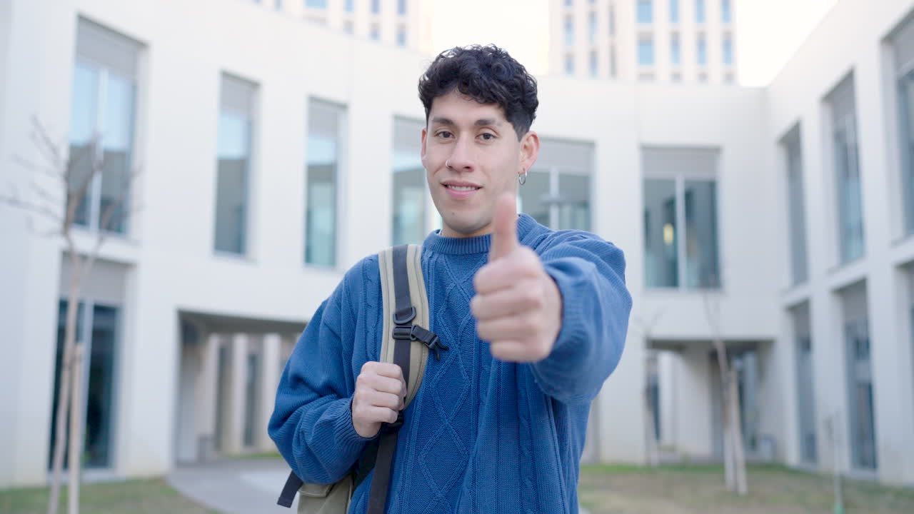 Man with backpack showing thumb up at campus