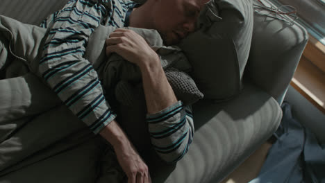 a sad man wakes up tired on his sofa