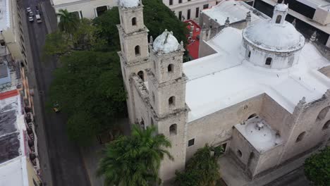Aerial-camera-slowly-turning-to-the-left-looking-down-on-the-towers-and-front-of-the-Rectory-Jesus-in-Merida,-Yucatan,-Mexico