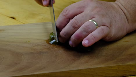 de chef-kok snijdt groene gepekelde hete pepers op een snijplank