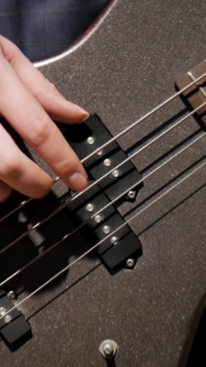 Close up of hands playing a bass guitar