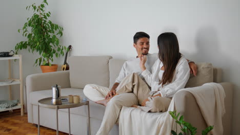 Smiling-couple-embracing-sofa-vertically-closeup.-Woman-stroking-man-relaxing